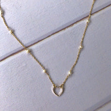 Cargar imagen en el visor de la galería, Dije labrado con cadena con perlas de agua. Baño en oro. Largo: 40cm con extensión ajustable de 5cm. Dije de aprox. 1cm de ancho.